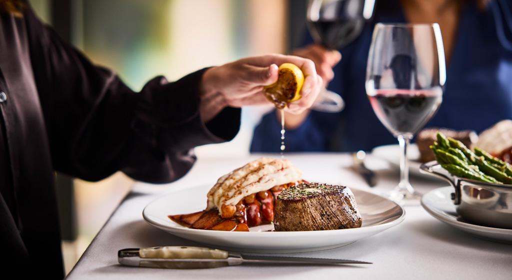 Diner squeezes fresh lemon on a lobster tail