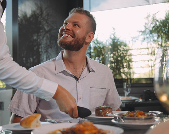 A happy Guest on patio looking at server while she places filet mignon on table