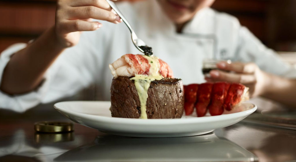Chef at Fleming's putting premium caviar on top of the lobster and filet mignon