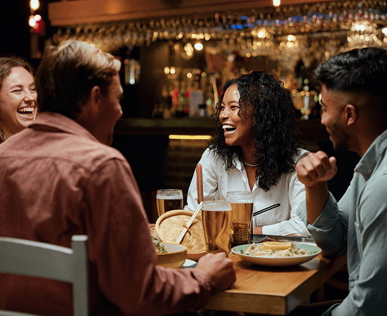 Group of friends enjoying food and drinks at a restaurant, highlighting connection and community.